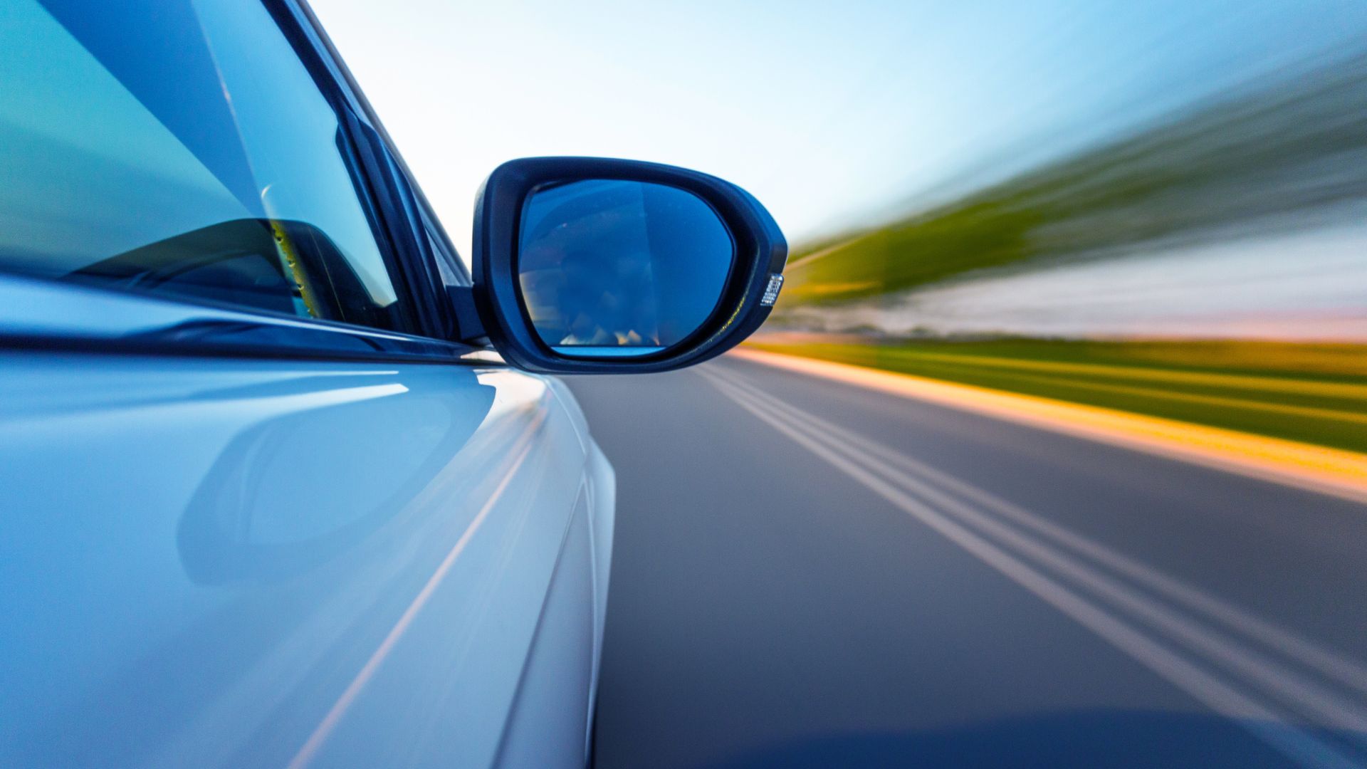 Car side mirror with blurred motion showing speed on highway