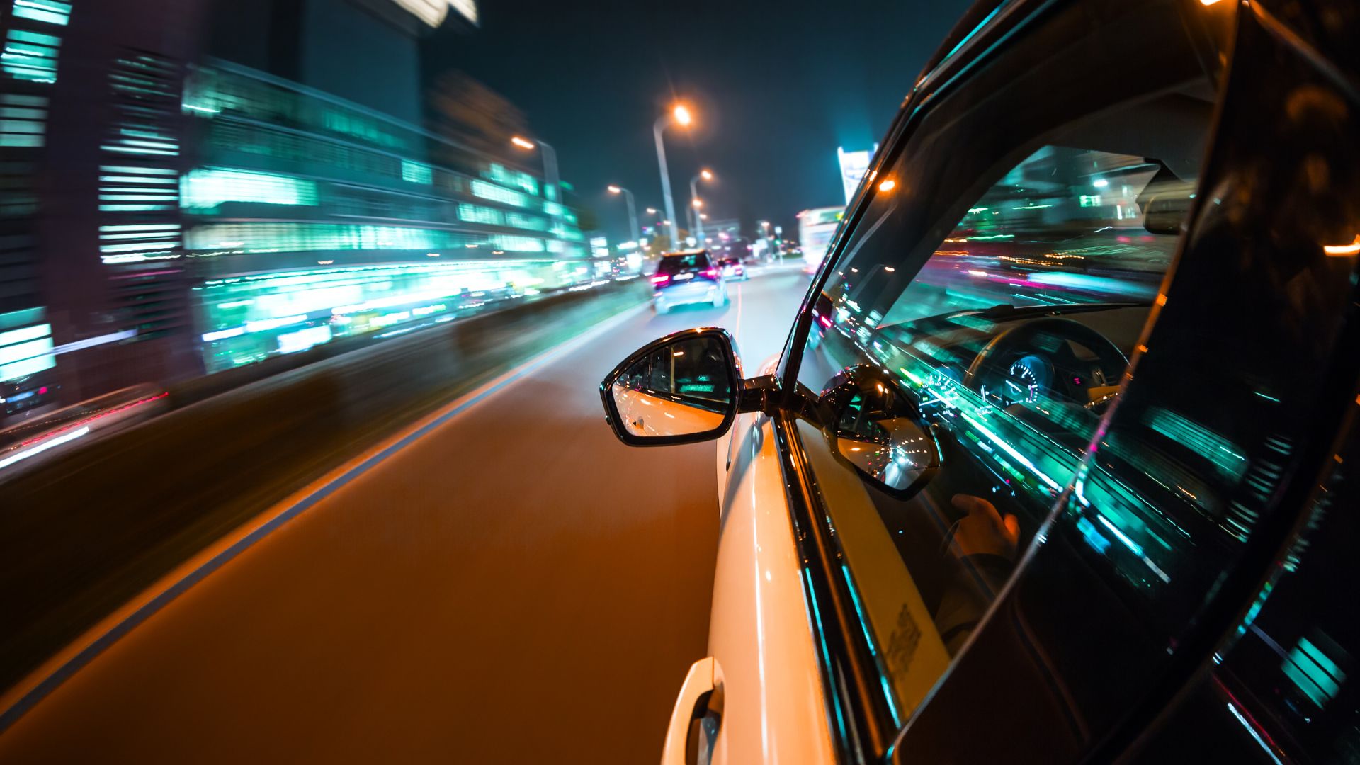 Night driving with motion blur, city lights streaking past car window