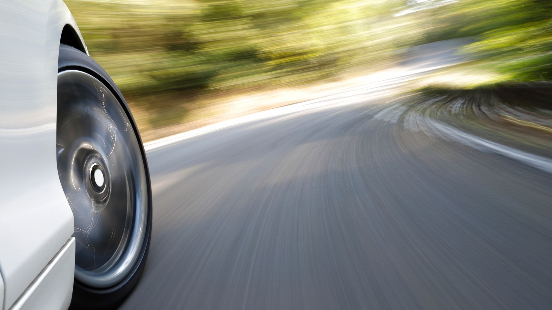 Blurred wheel of car speeding on winding road with motion blur